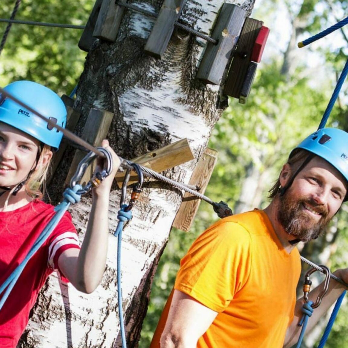 Två yngre tjejer och en man som klättrar i Höghöjdsbanan